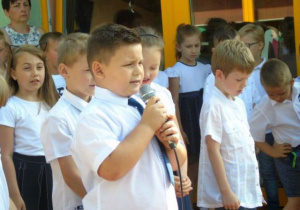 Grupa dzieci, chłopiec trzyma w rękuy mikrofon