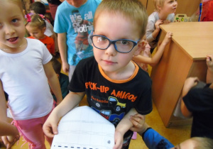Chłopiec w okularach trzyma kartkę.