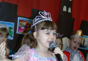 Dziewczynka w różowej sukience śpiewa piosenkę.
