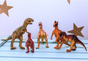 5 dinozarów stoi na skrzynce.