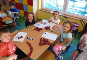 Dzieci siedzą przy stoliku i kolorują.
