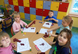 Dzieci siedzą przy stoliku i kolorują.