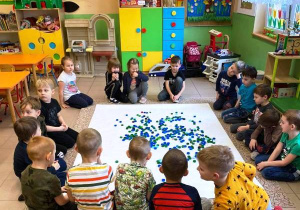Dzieci siedzą na podłodze i układają obrazek.