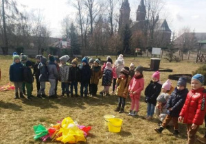 Dzieci stoją w ogrodzie przedszkolnym.