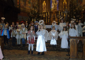 Dzieci przebrane za królów, pasterzy i anioły stoją w kościele