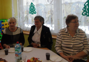Starsze kobiety siedzą przy białym stole