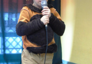 Chłopiec przebrany za niedziedzia trzyma mikrofon