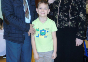 Mały chłopczyk w żółtej koszulce stoii z Dziadkami