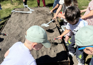 Dzieci przygotowują skrzynkę warzywniaka do wsiania nasion.