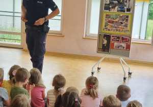 Pan policjant przeprowadza z dziećmi pogadankę.