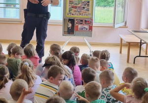 Pan policjant przeprowadza z dziećmi pogadankę.