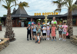 Grupa dzieci oraz dwie wychowawczynie stoją przez wejściem do zoo