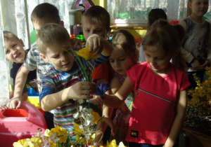 Dzieci robią palmę wielkanocną ze sztucznych kwiatów i suchych gałązek