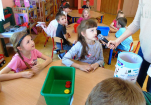 Grupa dzieci siedzi przy stoliku i mówi przez mikrofon