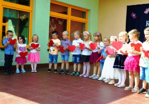 Dzieci trzymają w rączkach papierowe czerwone serca