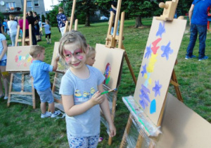 Dziewczynka maluje obrazek na sztaludze