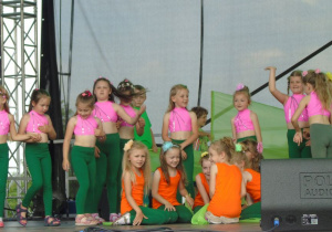 Dziewczynki w kolorowych strojach stoją na scenie