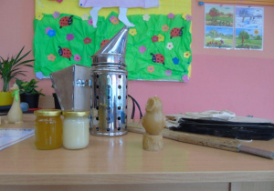 Na biurku stoi miód biały i złoty oraz świeca z wosku pszczelego