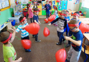 Dzieci z grupy Stokrotki tańczą przy muzyce trzymając w rękach czerwone baloniki w kształcie serca