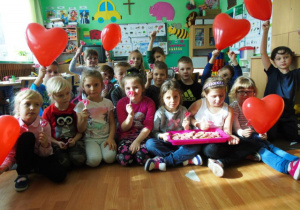 Dzieci z grupy Muchomorki trzymają w ręku lizaki i balony w kształcie serca- zdjęcie grupowe